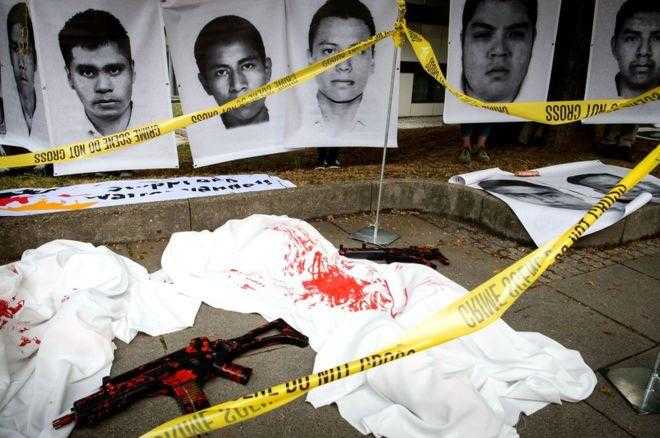 Images of the missing or murdered Mexican teachers in front of a "crime scene" with pretend guns covered in blood, surrounded by yellow crime scene tape.