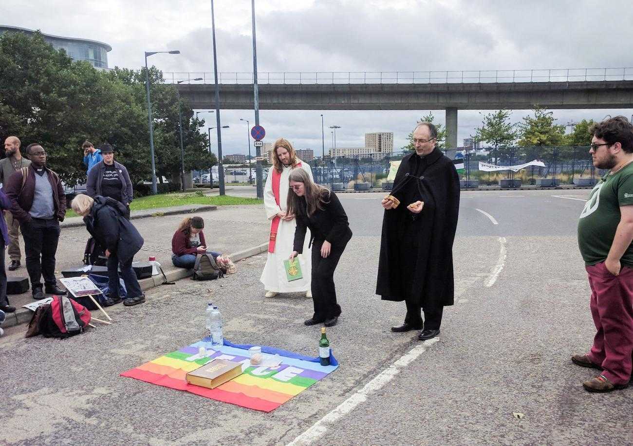 A group of prieces give communion at the DSEI protests