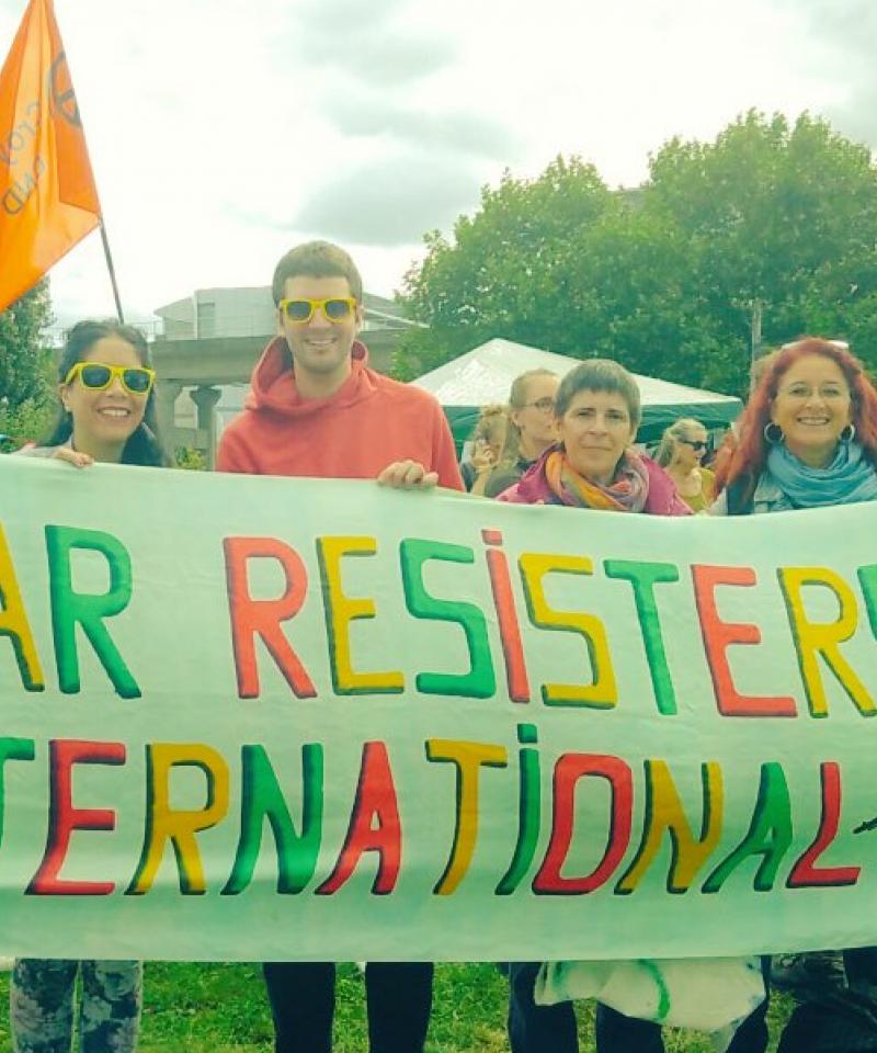 WRI activists hold a "War Resisters' Internaitonal" banner