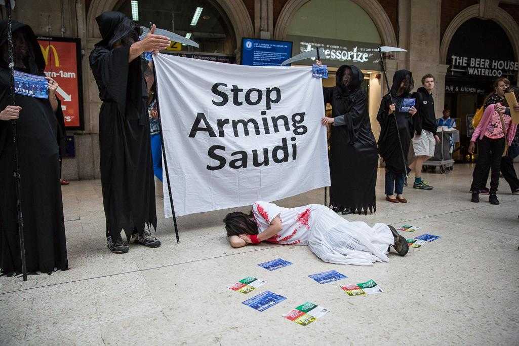 Activists dress in black "grim reaper" outfits and hold a banner reading "Stop Arming Saudi"