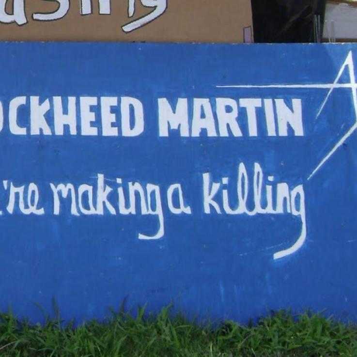 A protest banner mimic the Lockheed Martin logo. The sign reads "Lockheed Martin: we're making a killing"