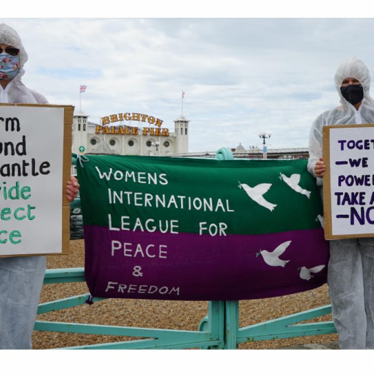 Dos activistas con monos blancos sostienen pancartas y carteles que relacionan la guerra y el cambio climático 